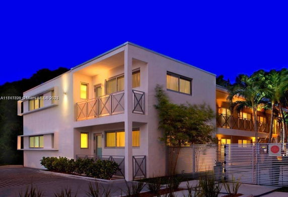 Front view of a modern two-story building with balconies and illuminated windows.