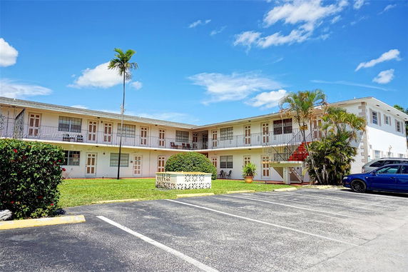 Front view of a two-story apartment building with a surrounding parking area.