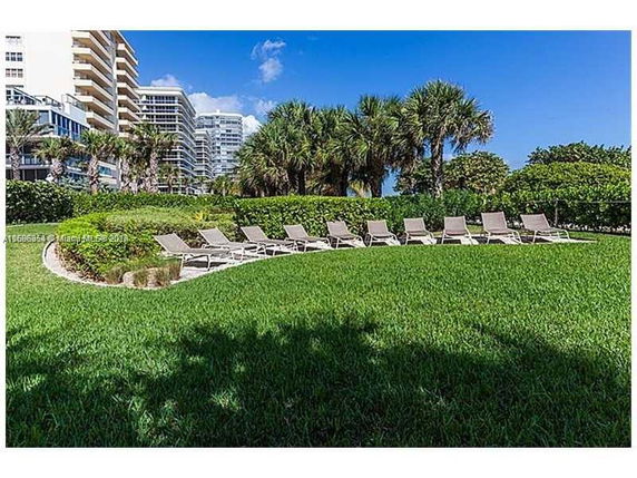 Tall apartment buildings with visible balconies surrounded by a lawn and palm trees.