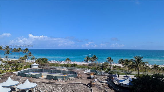 View of a beach and ocean with palm trees and construction site in the foreground.