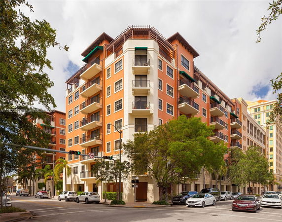 Front view of a multi-story residential building with balconies and trees.