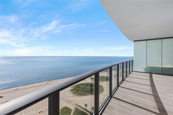 Outdoor balcony view of a coastline with clear blue skies and ocean.