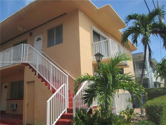Front view of a two-story building with an external staircase and a balcony.