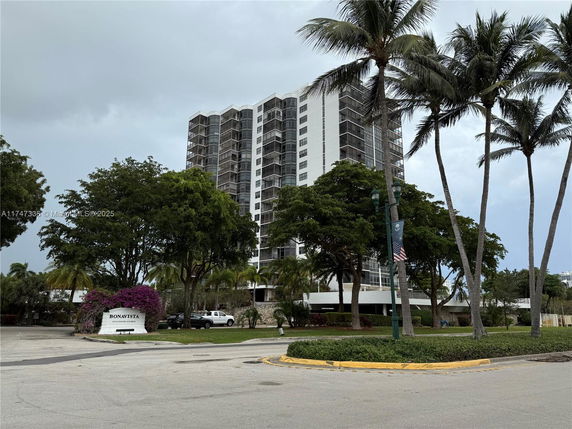 Front view of a high-rise residential building surrounded by trees.