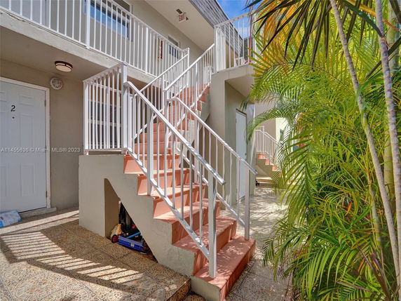 Front view of an apartment entrance with stairs and railings.