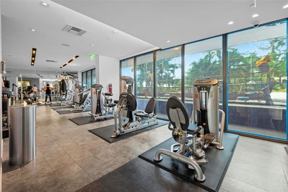 Indoor gym area with exercise machines and large windows.