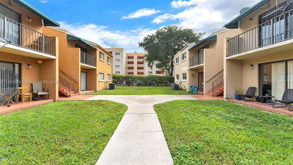 Outdoor view of residential buildings with balconies and a grassy courtyard.