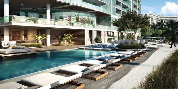 Luxury apartment building with glass balconies and poolside lounge area.