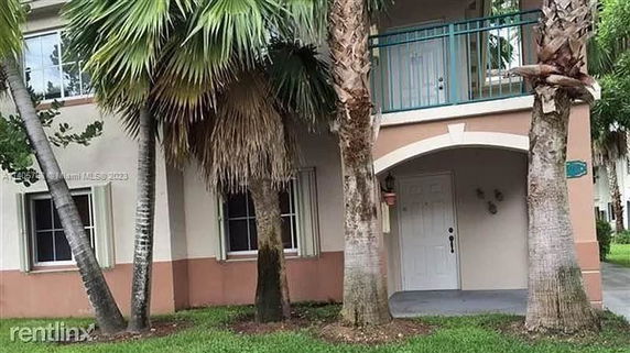 Front view of a two-story house with palm trees.