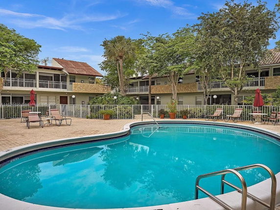 Outdoor swimming pool with surrounding lounge chairs and building in the background.