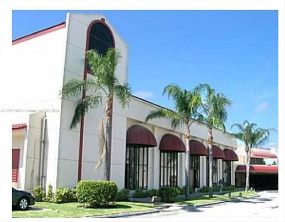Front view of a commercial building with large windows and red awnings.