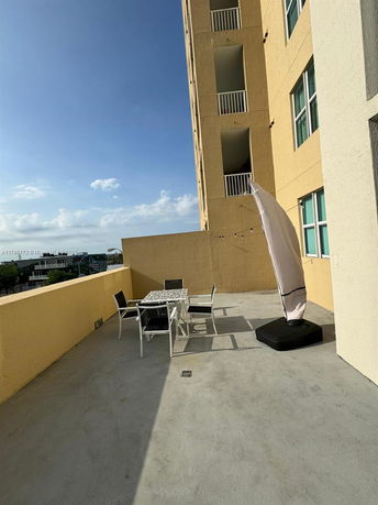 Building rooftop area with outdoor seating and a parasol.