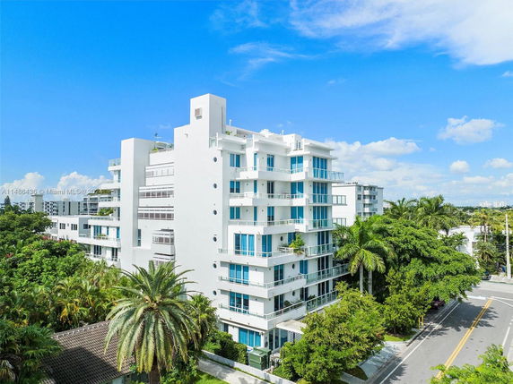 Front view of a multi-story residential building with balconies and glass windows.