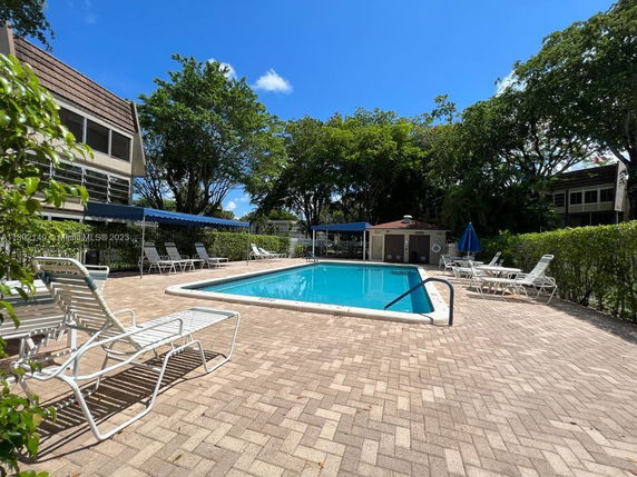 Outdoor swimming pool area with lounge chairs and surrounding greenery.