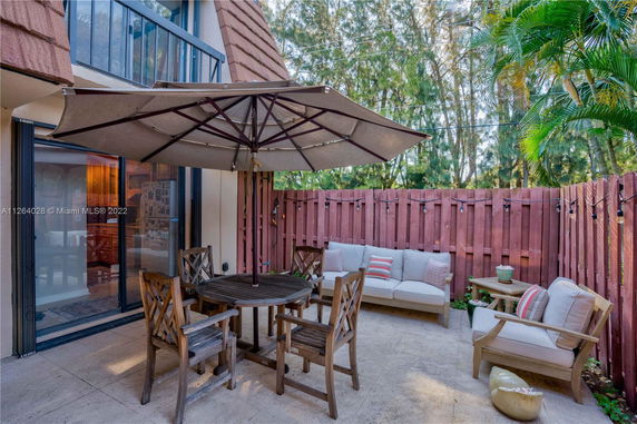 Outdoor patio area with seating, table and umbrella adjacent to building.