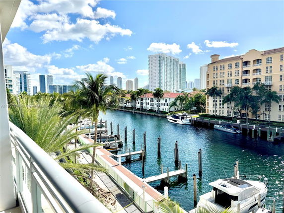View of waterfront buildings with boats and docks, high-rise buildings in the background.