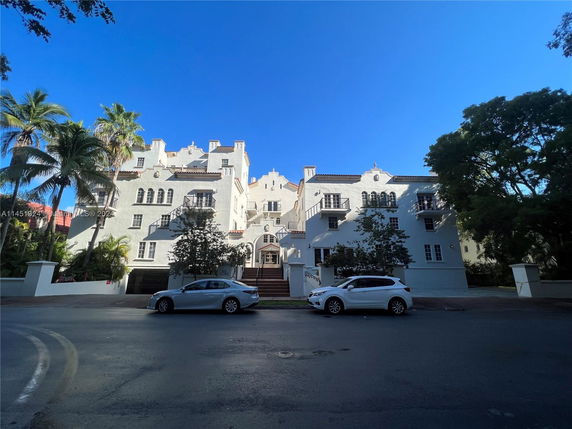 Front view of a multi-story building with a white facade and balconies.