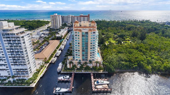 Aerial view of a high-rise apartment building with surrounding greenery and waterfront.