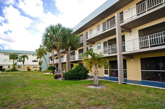 Front view of a three-story building with balconies and a lawn area.