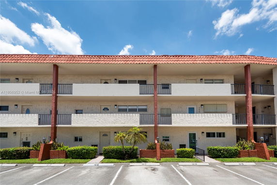 Front view of a multi-story residential building with balconies and a red-tiled roof.