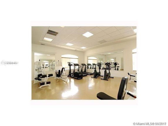 Indoor gym area with exercise equipment and large mirrors on the wall.