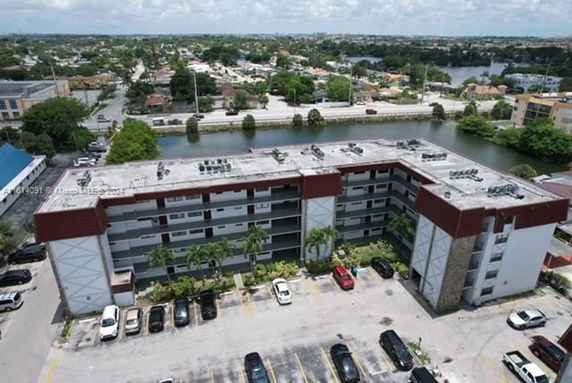 Aerial view of a multi-story apartment building with parking area in front.