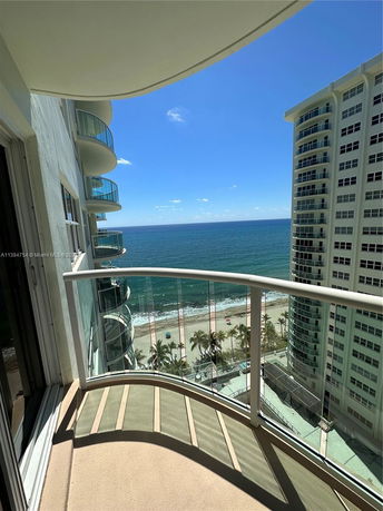 Balcony view overlooking the ocean and adjacent tall buildings.