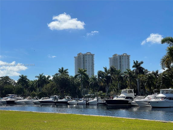 Tall buildings and boats on a waterway with palm trees in the foreground.