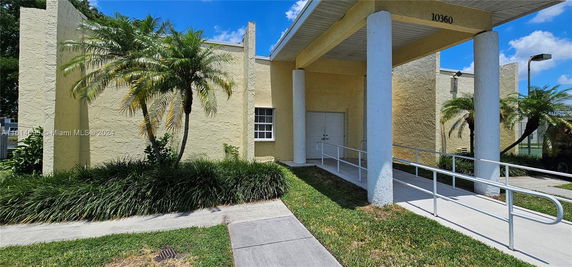 Front view of a building with a covered entrance and ramp.