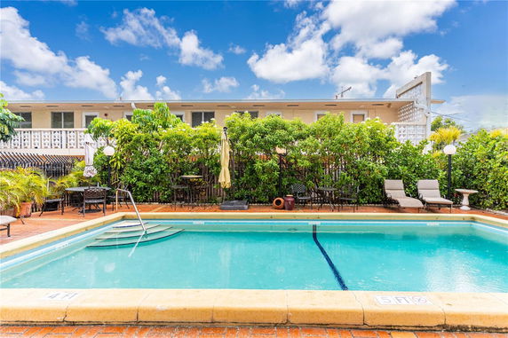 Outdoor swimming pool area with lounge chairs and greenery.