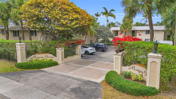 Front view of a residential complex entrance with sign reading 'Monterey Gardens' and parking area.