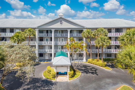 Front view of a multi-story residential building with balconies and a central driveway.