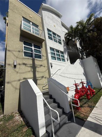 Front view of a multi-story building with balconies and stairs.