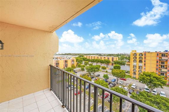 View from a balcony overlooking a parking lot and several apartment buildings.