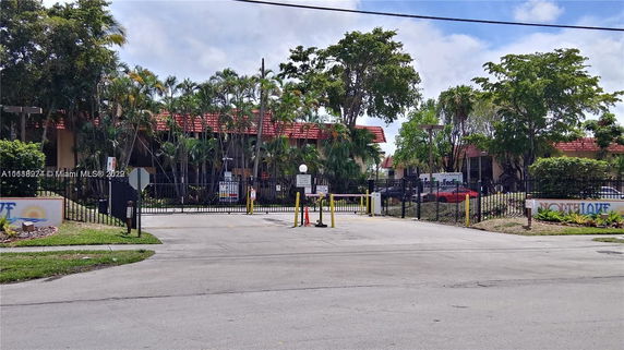 Front view of a gated building with a red roof, surrounded by trees.