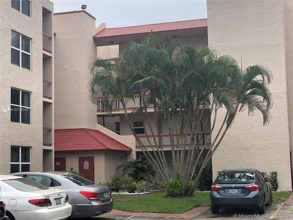 Front view of a multi-story building with red roofing and several balconies.