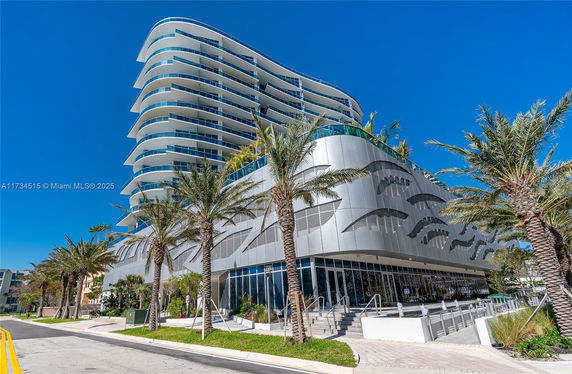 Front view of a modern multi-story building with curved balconies and decorative exterior panels.