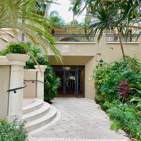 Front view of a building entrance with arched railings and potted plants.