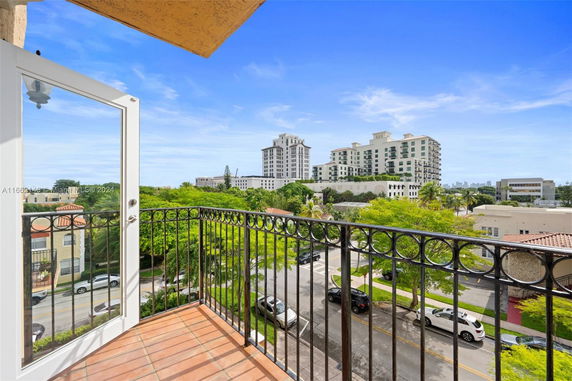 View from a balcony overlooking a cityscape with modern buildings under a clear blue sky.
