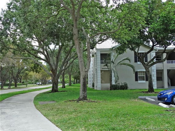 Front view of a two-story residential building with a textured facade and a white roof.