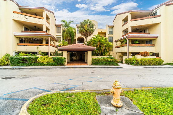 Front view of a multi-story apartment building with balconies and an entrance canopy.