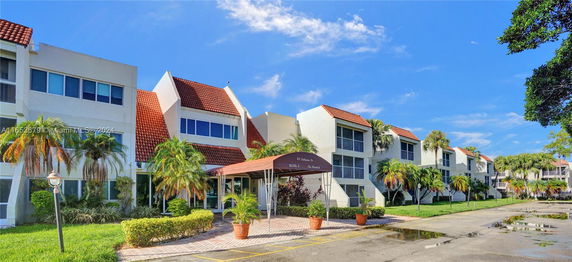 Front view of a multi-story building with a canopy entrance and red tiled roofs.