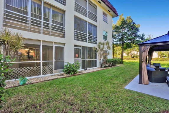 Side view of a multi-story building with large windows and a garden area with outdoor seating.