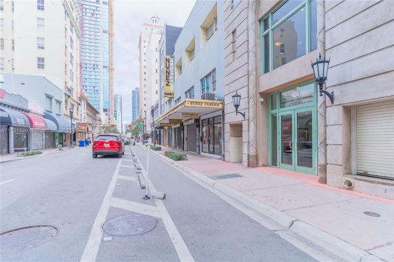 Street view of commercial buildings with storefronts and adjacent high-rise structures.
