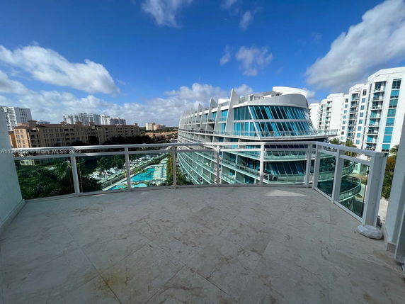 Panoramic view from a balcony overlooking modern buildings and a swimming pool.