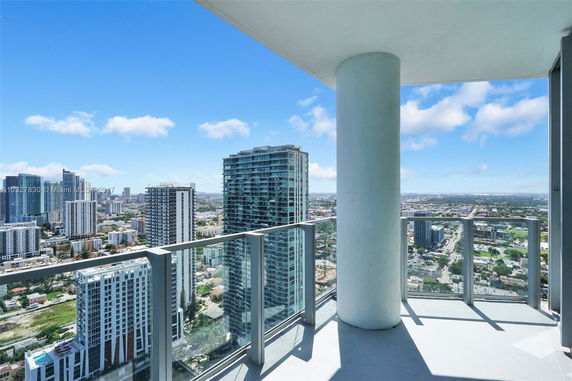 View from a high-rise balcony overlooking a cityscape with numerous tall buildings.