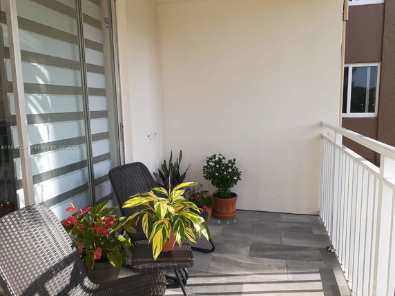 Outdoor balcony with chairs and potted plants.