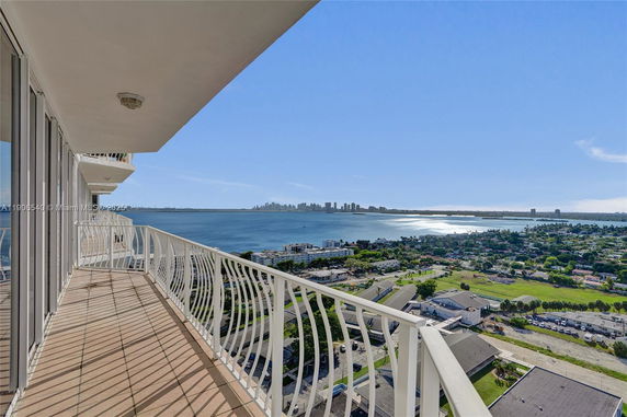 Panoramic view from a high-rise building balcony overlooking a coastal cityscape and ocean.