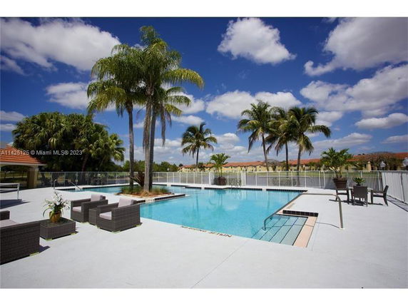 Outdoor swimming pool area with palm trees and seating.