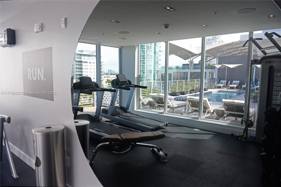 Indoor gym area with exercise equipment and a view of an outdoor pool.